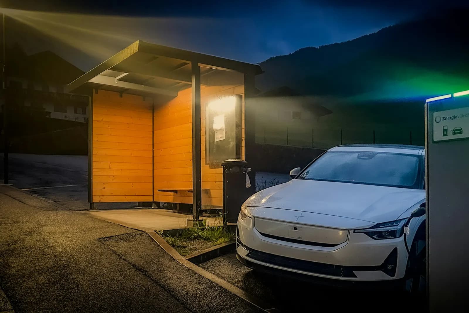 White electric car charging at a station at night