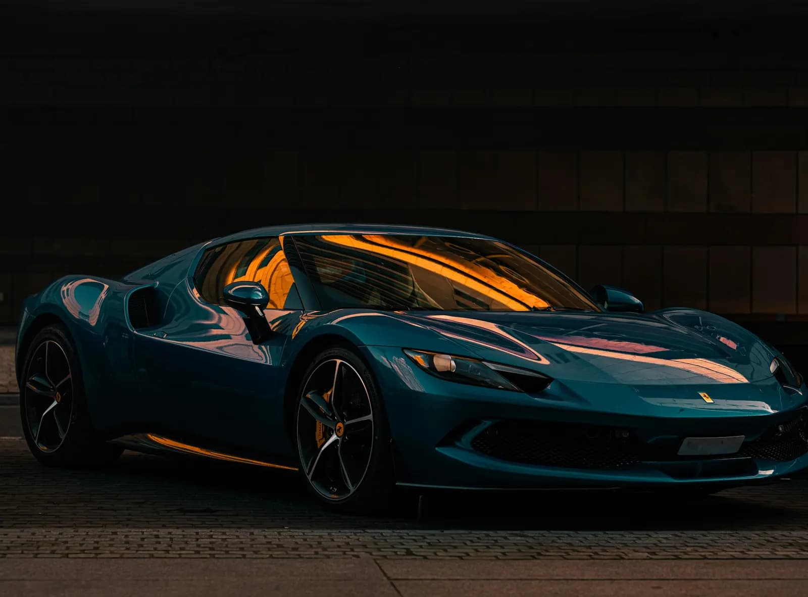 Blue Ferrari 296 parked at night under warm lights