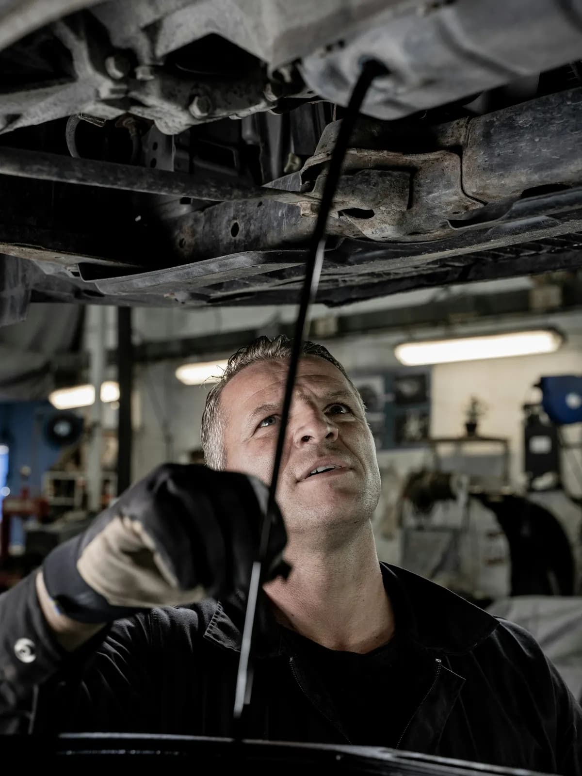 Technician inspecting the underside of a car on a lift