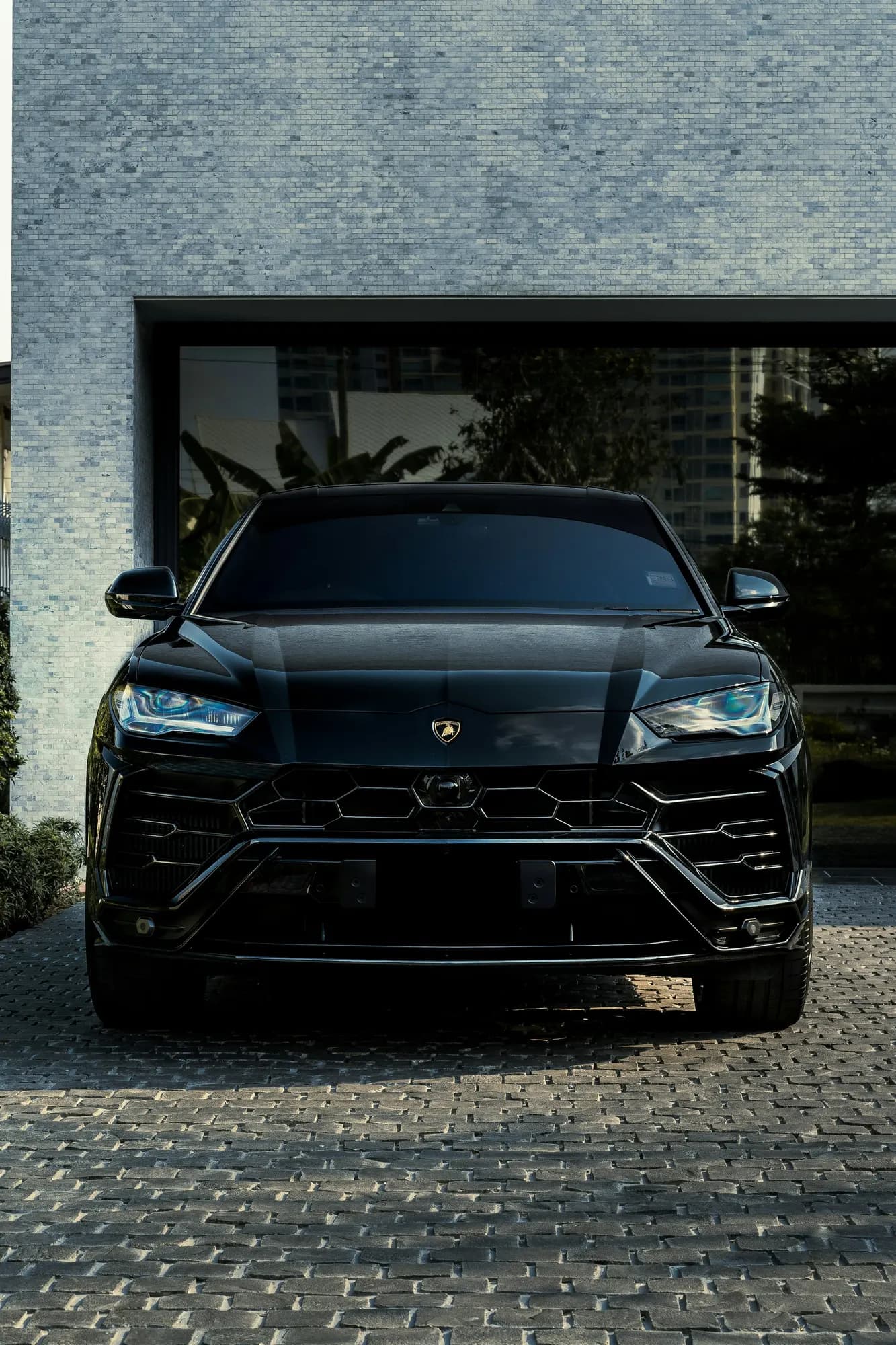 Black Lamborghini Urus, front view in front of a dark garage