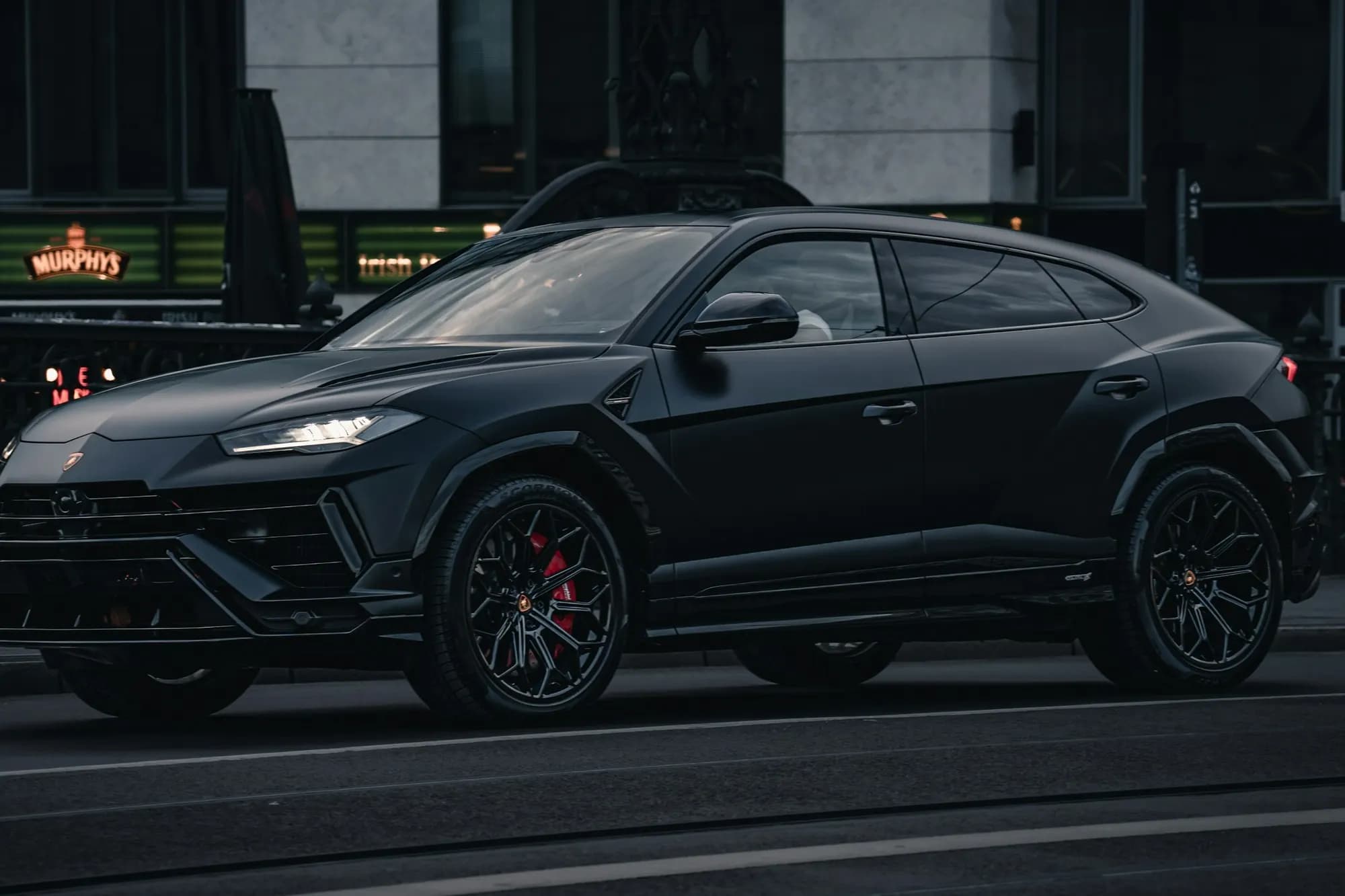 Black Lamborghini Urus, side view on a city street