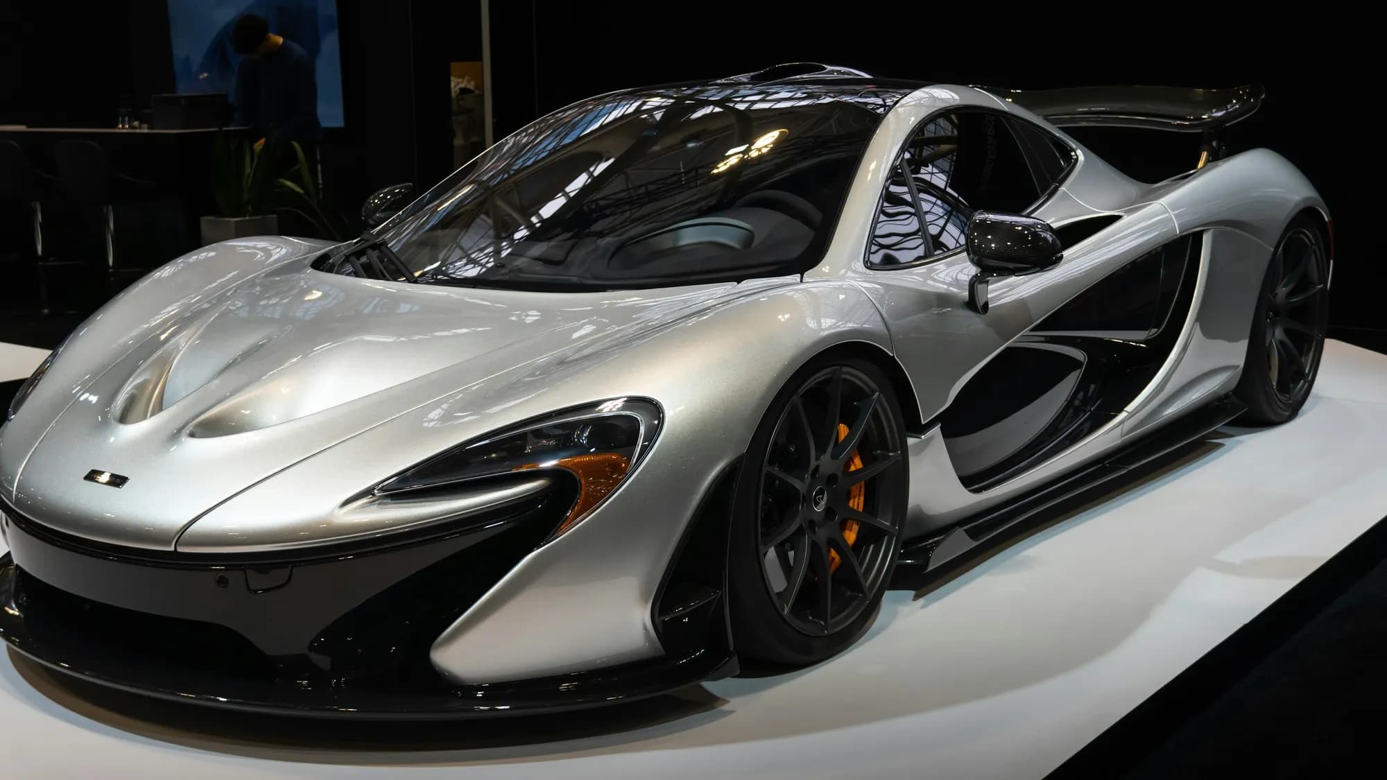 Silver McLaren P1, front three-quarter view on a dark stage