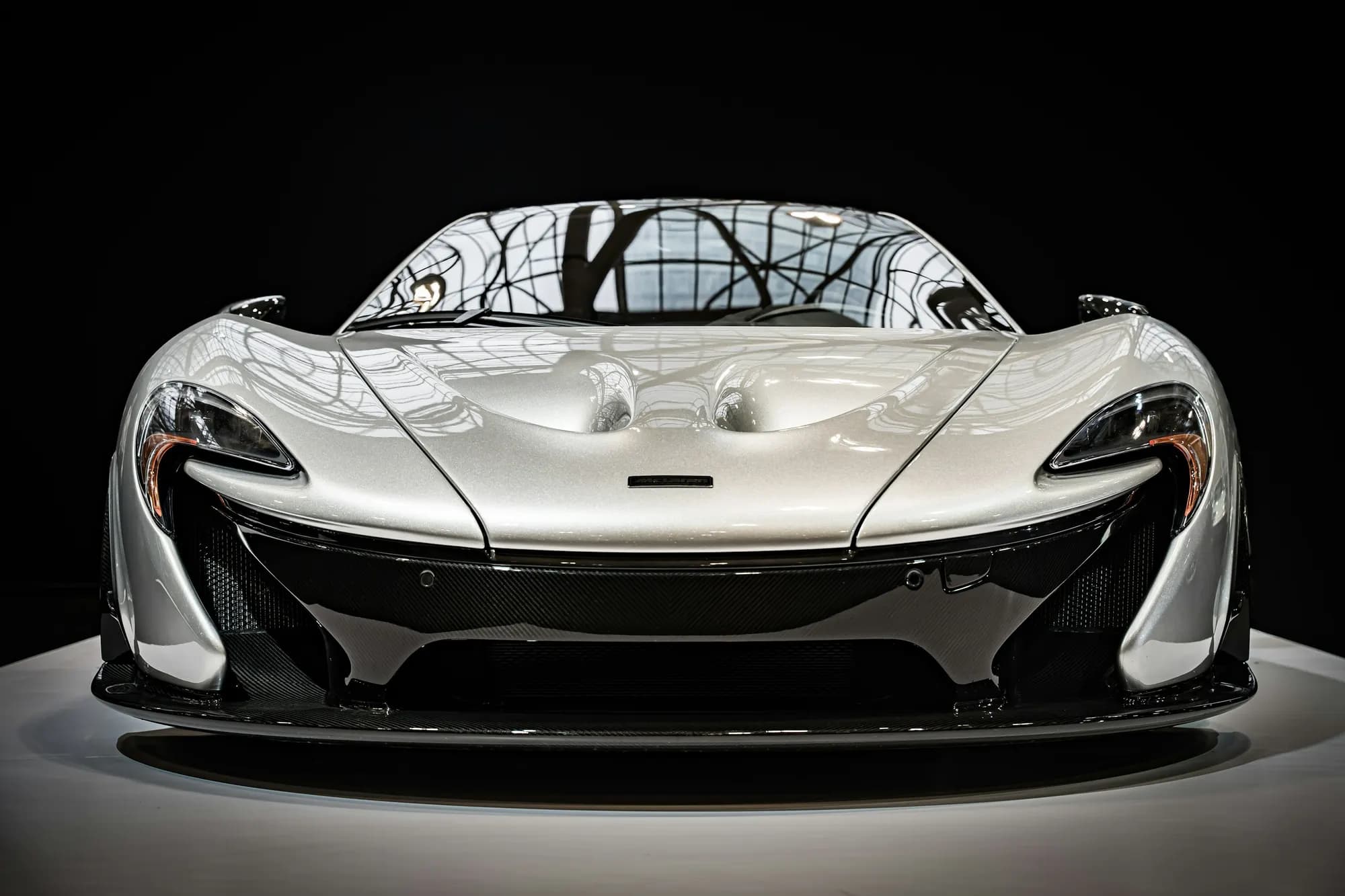 Silver McLaren P1, head-on front view in a dark studio